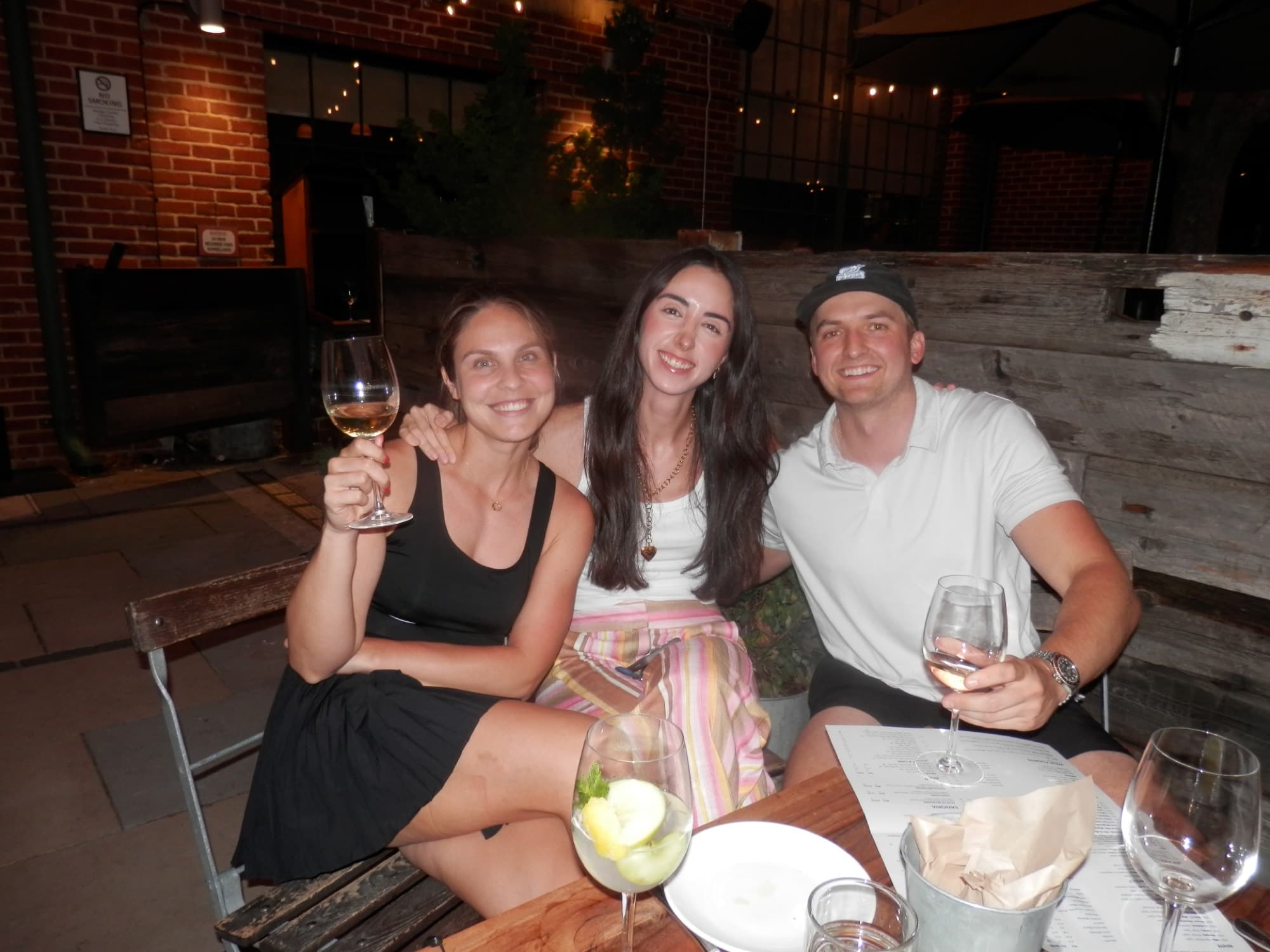 Three Tardeo players raising wine glasses at the patio table
